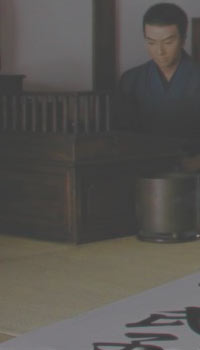 Eine Japanische Schreibwerkstatt. Ein junger Mann sitzt an einem Schreibpult